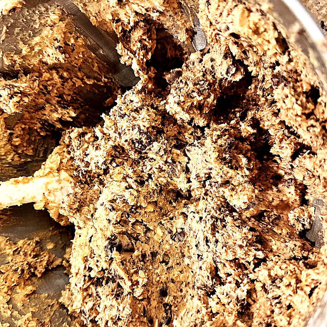 Chocolate chip cookie dough being mixed by hand