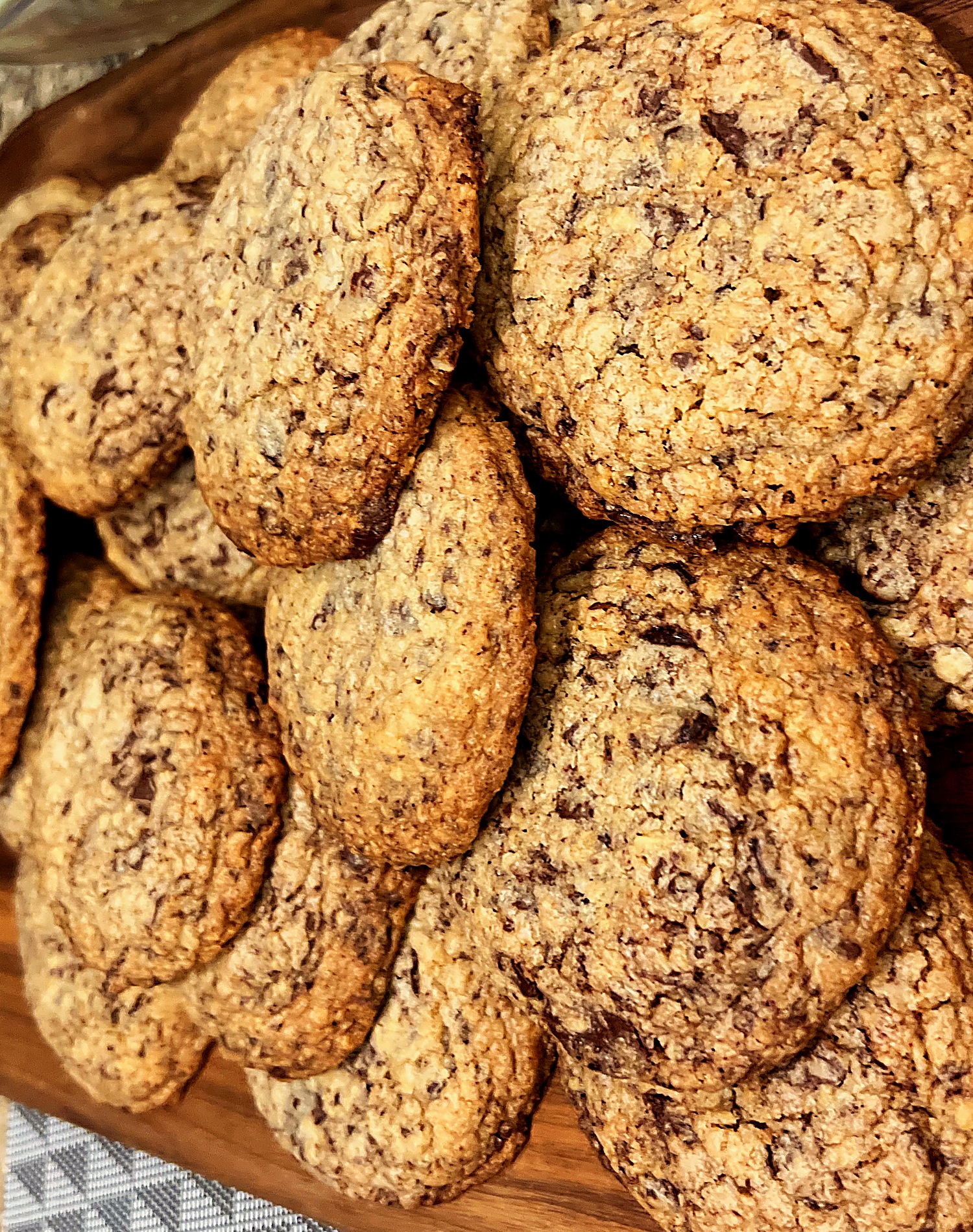 Freshly baked Real Cookie Co. chocolate chip cookies on a walnut board